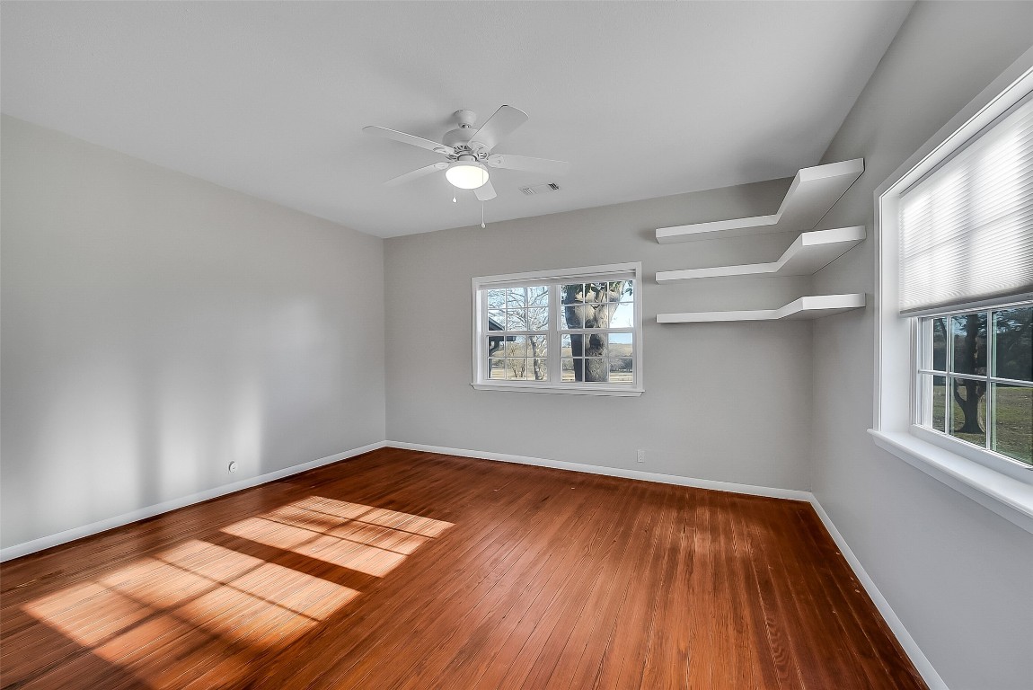 1005 Church Street Brenham, TX 77833 - Photo 27 of 44 an empty room with wooden floor chandelier fan and windows