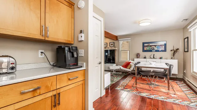 a living room with stainless steel appliances kitchen island granite countertop a refrigerator and cabinets