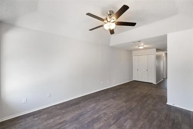 an empty room with wooden floor and a ceiling fan