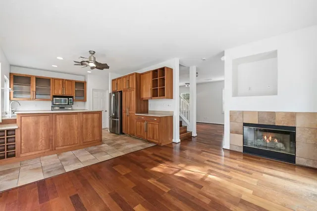 a living room with stainless steel appliances furniture a fireplace and a kitchen view