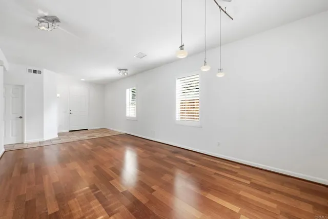 an empty room with wooden floor and windows