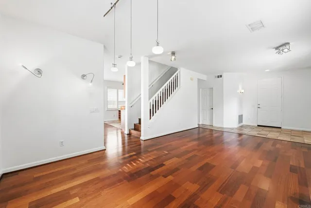 a view of an empty room with wooden floor and white walls