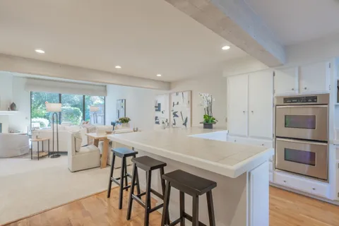 a view of kitchen with kitchen island a stove a table and chairs in it