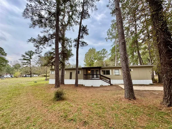 a view of a house with a large tree and wooden fence