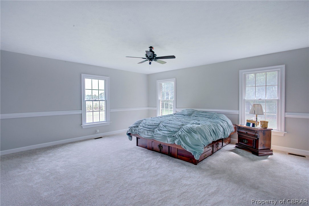 140 Mill Point Road Hudgins, VA 23076 - Photo 25 of 47 a spacious bedroom with a bed chandelier and windows