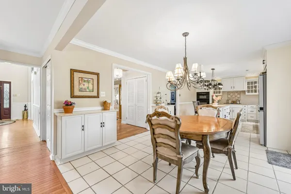 a dining room filled a chandelier and kitchen view