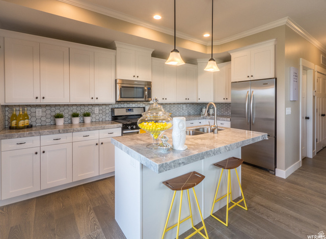 9294 South Rose Cottage Way, Unit 207 Sandy, UT 84094 - Photo 4 of 10 Kitchen featuring white cabinets, stainless steel appliances, tasteful backsplash, light countertops, and crown molding