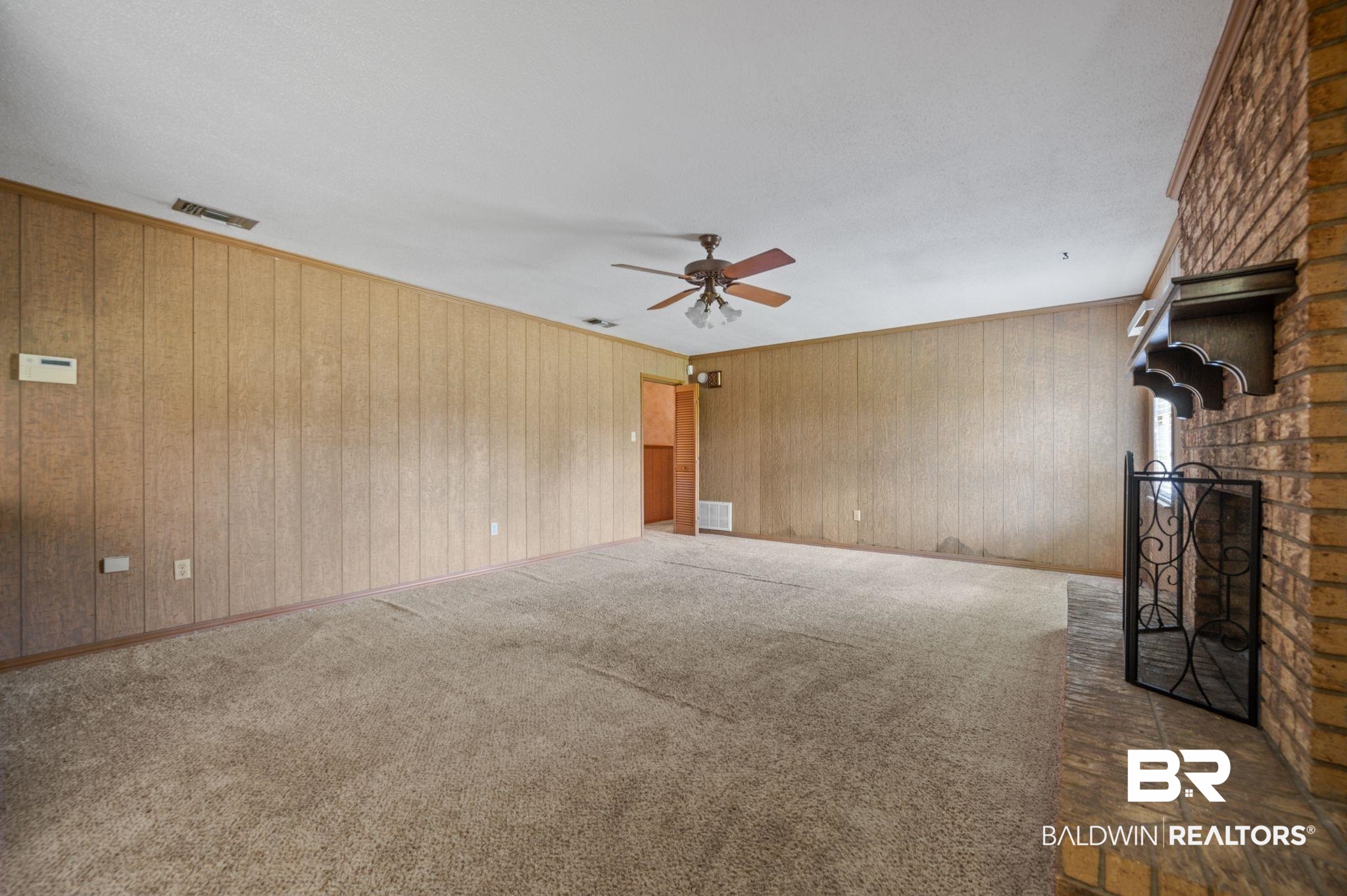 15880 Pine Grove Rd Extension West Bay Minette, AL 36507 - Photo 26 of 44 Unfurnished living room with wood walls, a brick fireplace, ceiling fan, and dark carpet