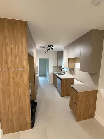 a kitchen with stainless steel appliances kitchen island granite countertop a refrigerator and a sink