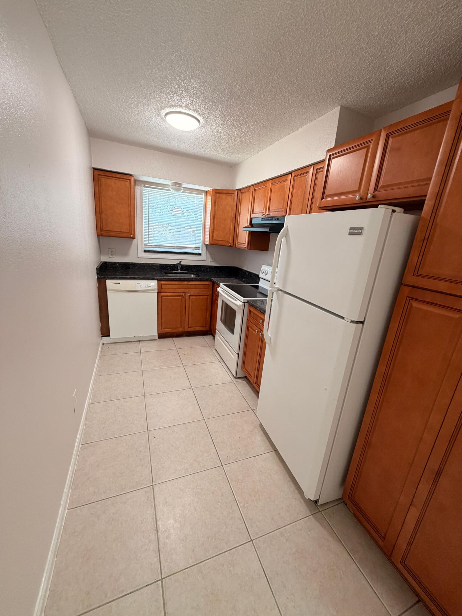 1618 West 26th Court, Unit A Riviera Beach, FL 33404 - Photo 5 of 15 a kitchen with a refrigerator and more cabinets