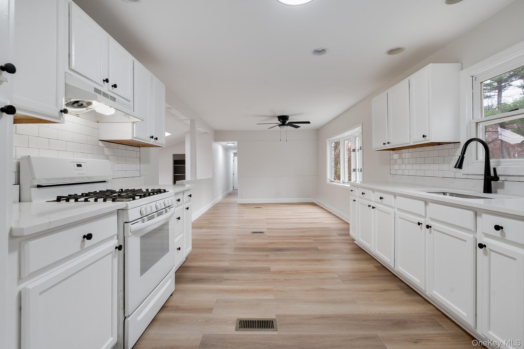 356 Sands Road Middletown, NY 10941 - Photo 10 of 22 a kitchen with white cabinets a sink dishwasher and a stove with wooden floor