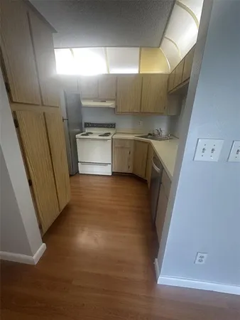 a view of a refrigerator in kitchen and an empty room