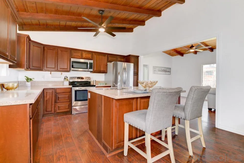 1105 Hamlet Drive El Cajon, CA 92021 - Photo 5 of 26 a kitchen with stainless steel appliances granite countertop a stove top oven a sink a dining table and chairs with wooden floor