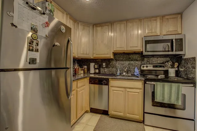 a kitchen with stainless steel appliances granite countertop a refrigerator a stove a sink and a microwave