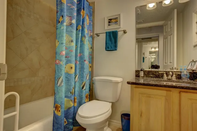 a bathroom with a granite countertop toilet sink and mirror