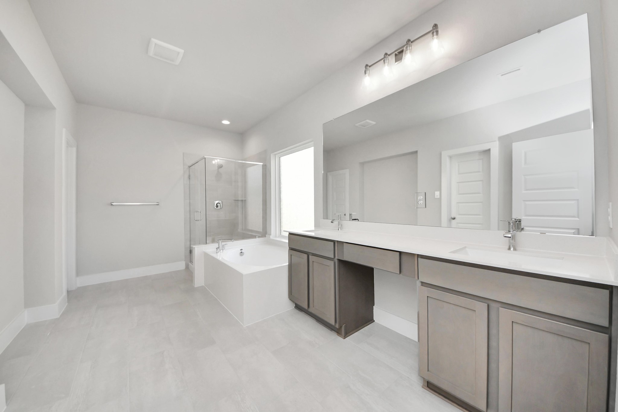 3042 Native Spg Drive Spring, TX 77373 - Photo 25 of 32 Escape to a spa-like oasis in this primary bathroom. Enjoy a walk-in shower with tile surround, a separate garden tub with custom detailing, and an elegant vanity featuring light countertops, modern hardware, and beautiful vanity lights. Experience luxury and relaxation in every detail. Sample photo of completed home with similar floor plan. Actual colors and selections may vary.