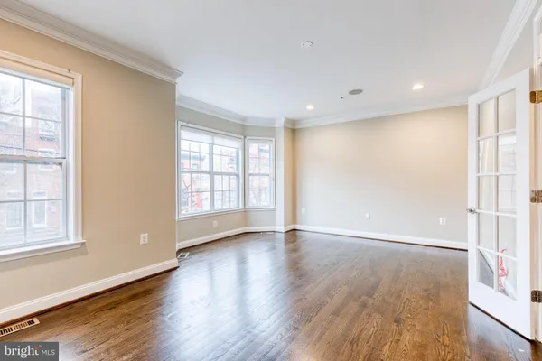 an empty room with wooden floor and windows