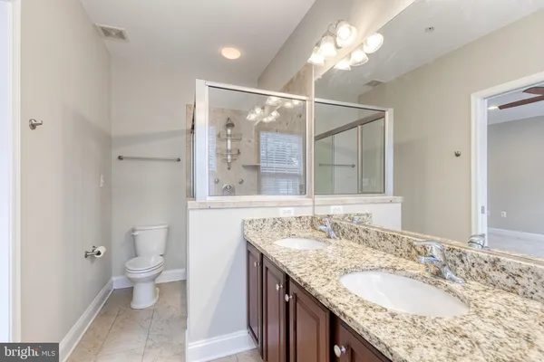 a bathroom with a granite countertop double vanity and a mirror