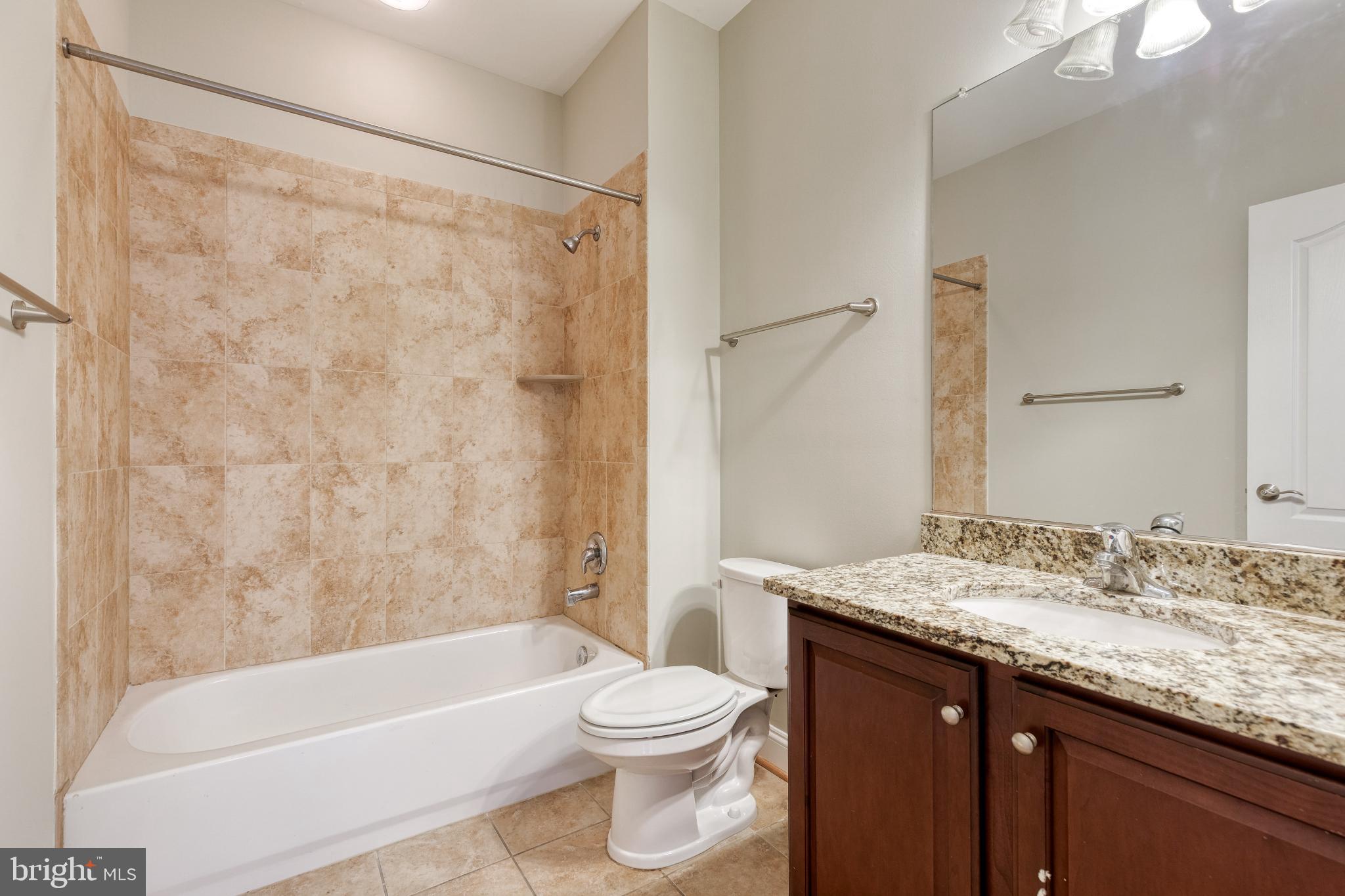 3307 Fait Avenue Baltimore, MD 21224 - Photo 5 of 26 a bathroom with a granite countertop sink a toilet a mirror and shower