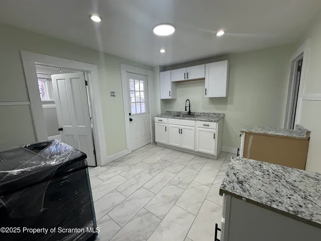 a kitchen with granite countertop a sink a stove top oven and cabinets