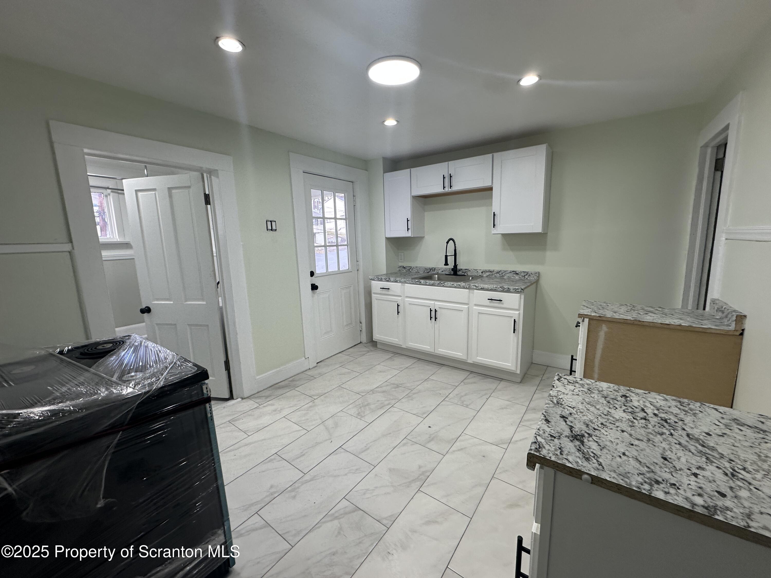 a kitchen with granite countertop a sink a stove top oven and cabinets
