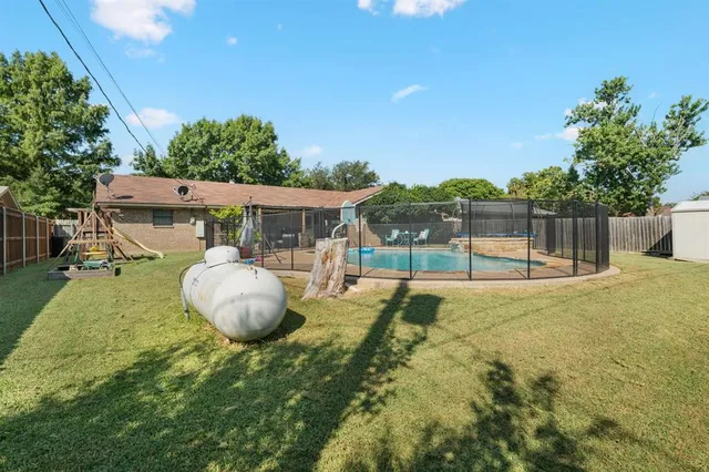 a view of a swimming pool with a patio and a yard
