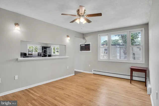 a view of an empty room with window and wooden floor