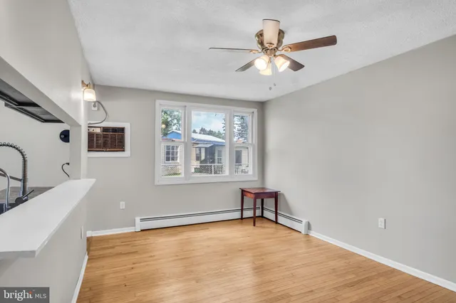 a view of an empty room with window and wooden floor