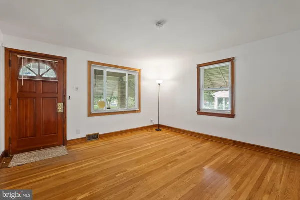 a view of an empty room with window and wooden floor