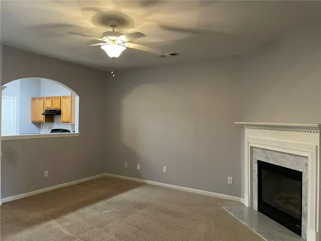 a view of a livingroom with a fireplace a chandelier fan and wooden floor