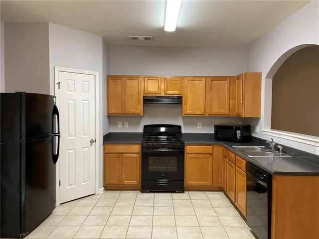 a kitchen with a refrigerator a stove a sink a washer dryer and cabinets
