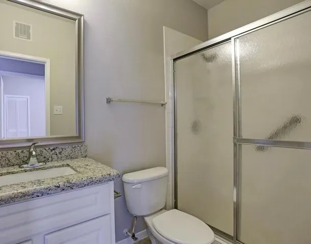 a bathroom with a granite countertop sink toilet and shower