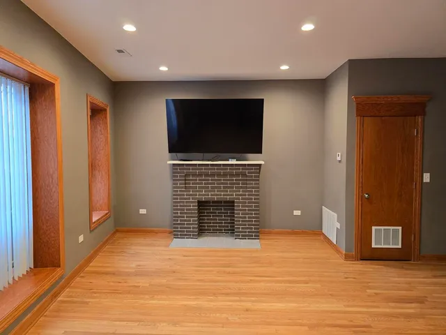 a view of an empty room with wooden floor and a fireplace