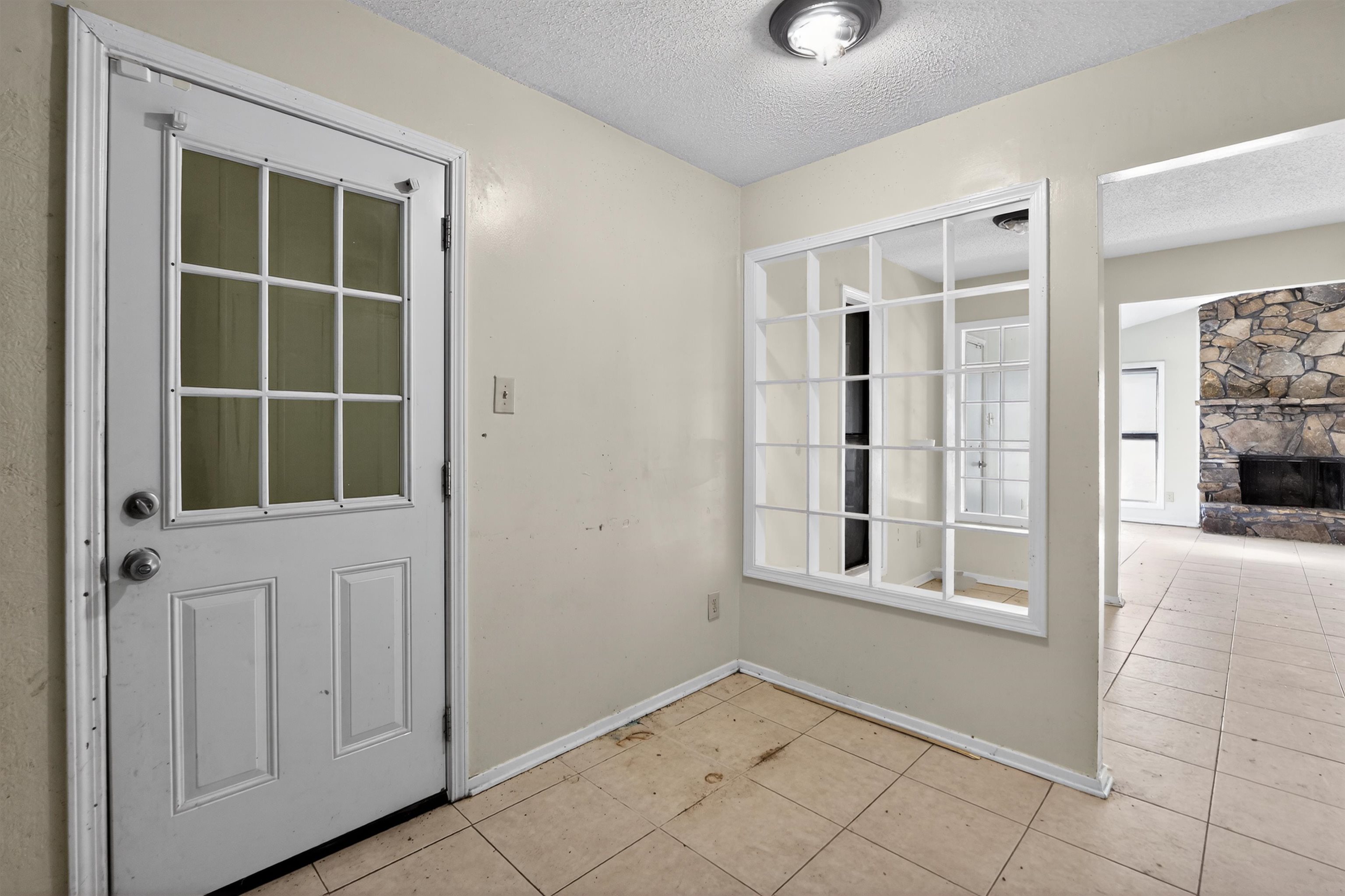 3372 Spring Shadow Drive Memphis, TN 38118 - Photo 12 of 35 Entryway featuring a paneled door with divided lite glass, tiled flooring, a decorative interior window, and a stone fireplace visible in the background
