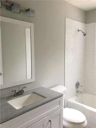 a bathroom with a granite countertop sink toilet and shower