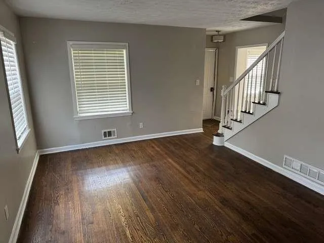 a view of an empty room with wooden floor and a window