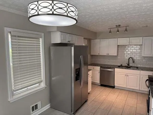 a kitchen with stainless steel appliances granite countertop a sink a stove a refrigerator cabinets and a dining table