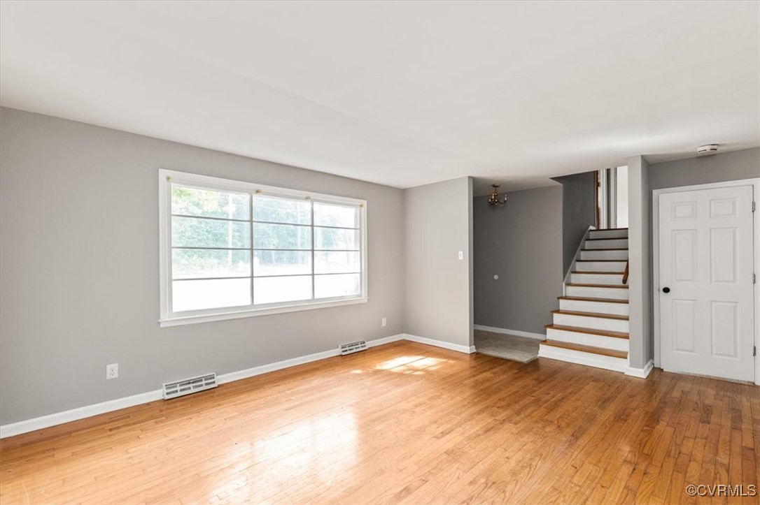 Empty room with wood finished floors, stairway, an
