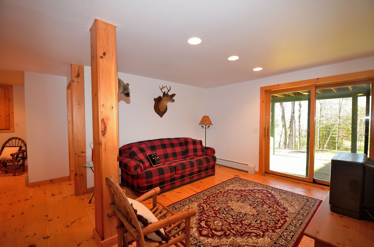 697 Woodmere Road Becket, MA 01223 - Photo 20 of 23 a living room with a couch and a dresser next to a window