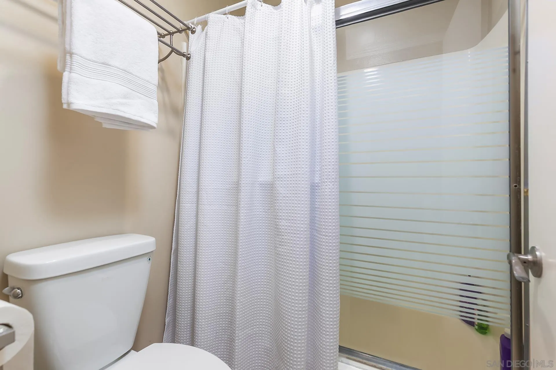 4878 Pescadero Avenue, Unit 103 San Diego, CA 92107 - Photo 35 of 72 a white toilet sitting next to a shower curtain