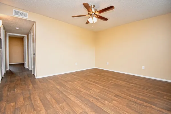 a view of a big room with wooden floor and a chandelier fan