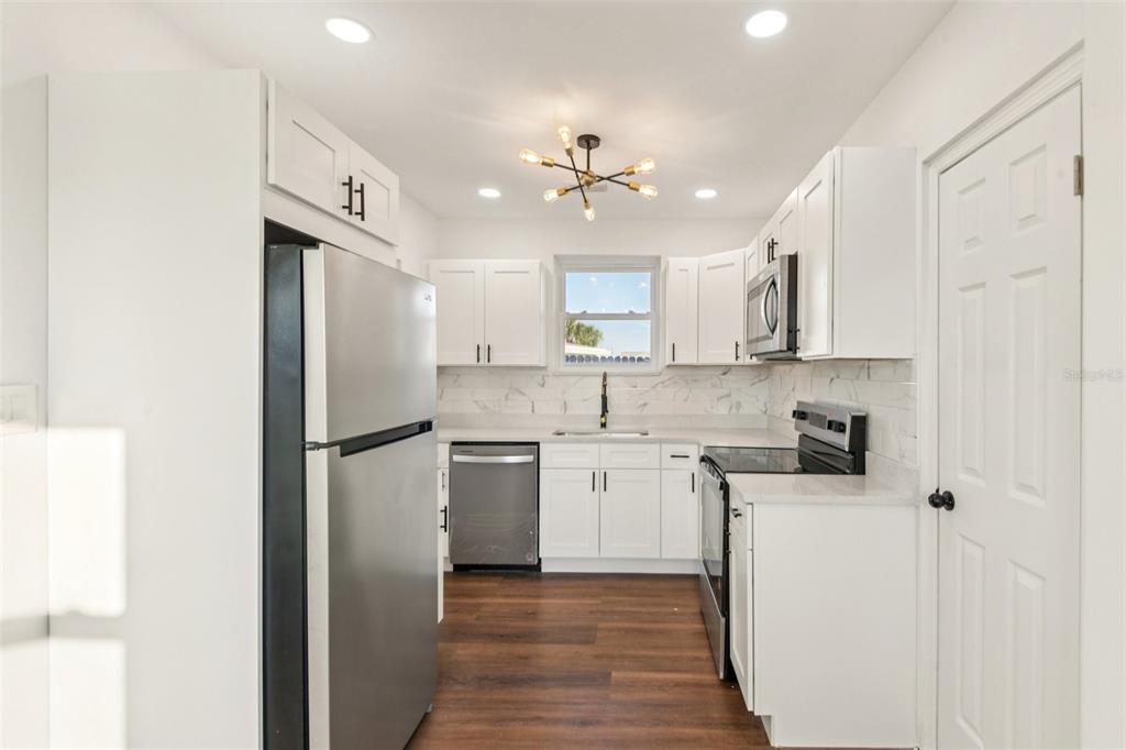 410 Virginia Avenue Madeira Beach, FL 33708 - Photo 9 of 25 a kitchen with a refrigerator a sink and dishwasher with white cabinets