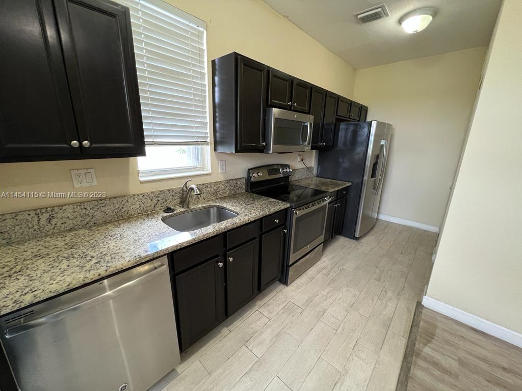 17182 Southwest 92nd Street Miami, FL 33196 - Photo 42 of 46 a kitchen with stainless steel appliances granite countertop a sink stove microwave refrigerator and cabinets