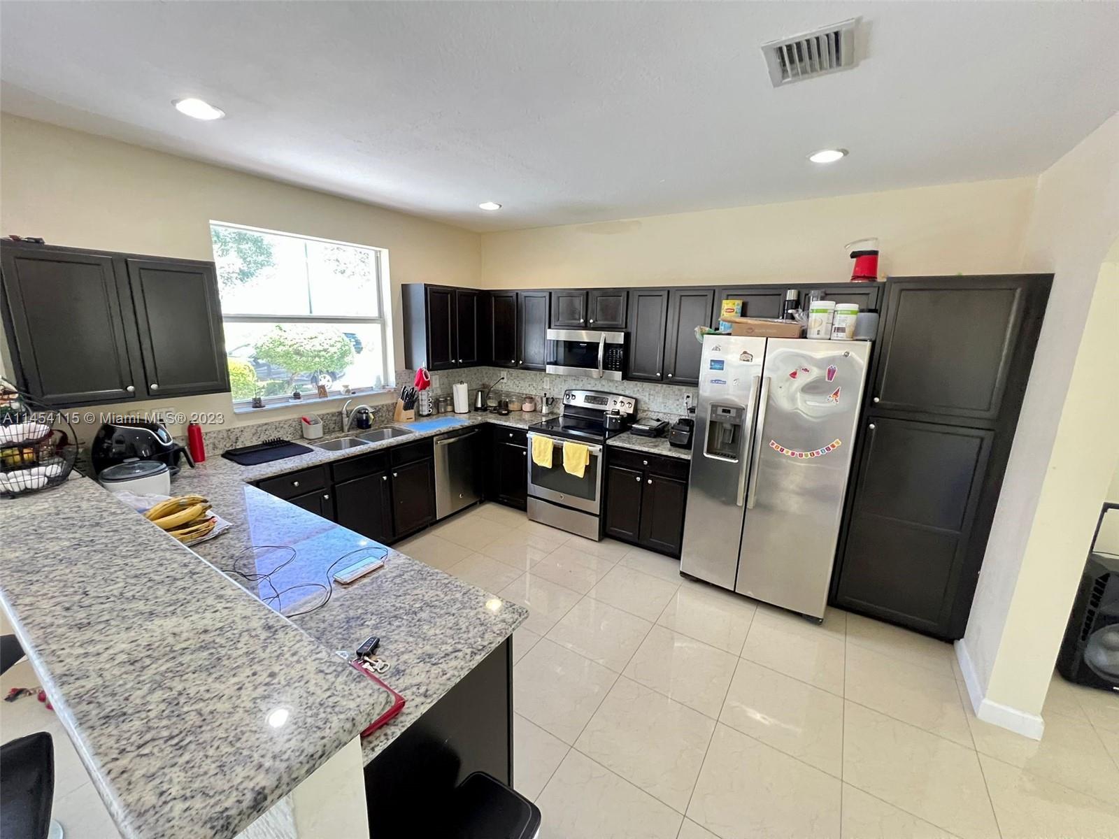 17182 Southwest 92nd Street Miami, FL 33196 - Photo 7 of 46 a kitchen with stainless steel appliances granite countertop a sink dishwasher stove top oven a refrigerator and dishwasher
