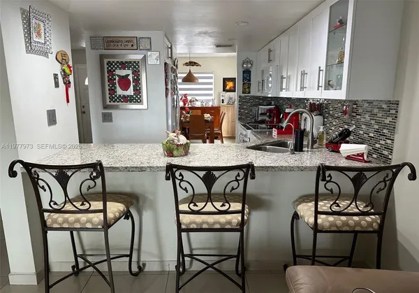 a kitchen with stainless steel appliances granite countertop a stove top oven a dining table and chairs with wooden floor