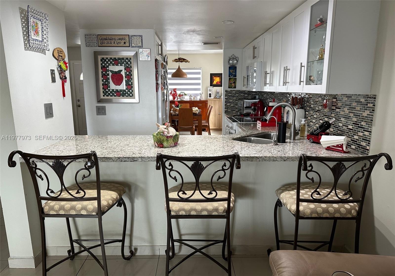 2385 West 69th Street, Unit 2385A Hialeah, FL 33016 - Photo 4 of 22 a kitchen with stainless steel appliances granite countertop a stove top oven a dining table and chairs with wooden floor