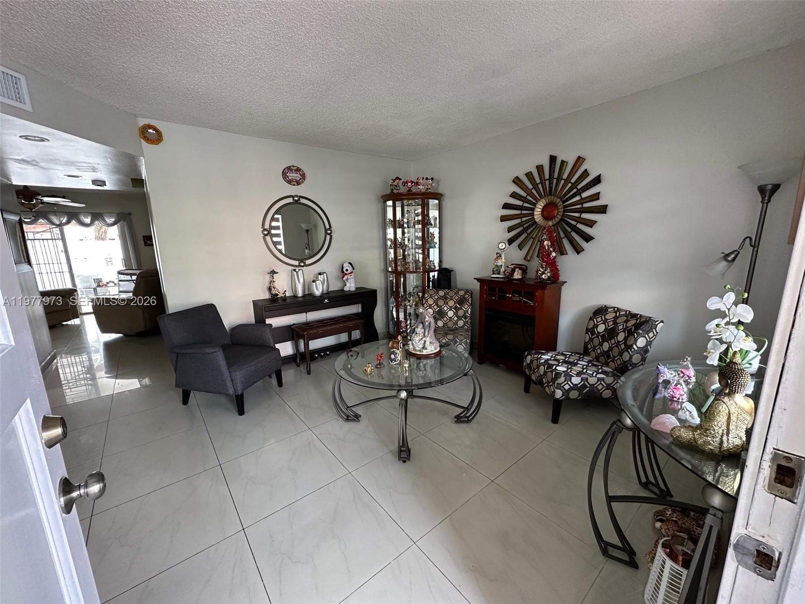 2385 West 69th Street, Unit 2385A Hialeah, FL 33016 - Photo 6 of 22 a living room with furniture flowers and a chandelier