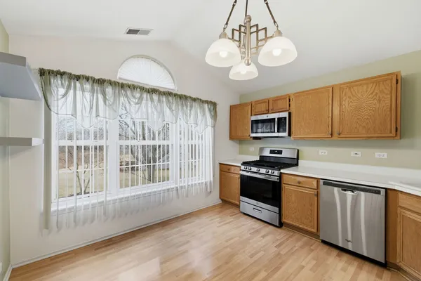 a kitchen with granite countertop stainless steel appliances a stove and wooden floor