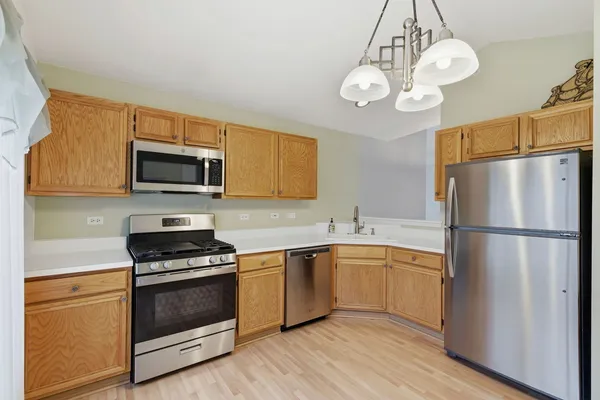 a kitchen with a sink stainless steel appliances and wooden floor