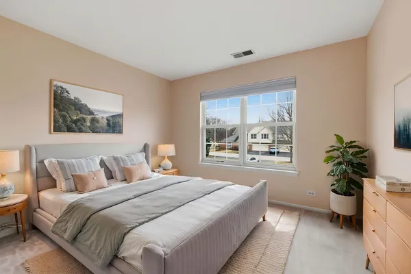 a spacious bedroom with a large bed and a potted plant
